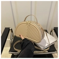 Detail of beige crescent bag with V-shaped quilting and gold metal zipper on a chair - Khaki