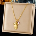 Detail van gouden zeepaardje en roze zeester hangers aan een kralenketting op doos - Gouden Zeepaardje Met Roze Zeester (N3468)