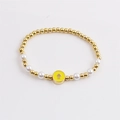 Goldenes Perlenarmband mit weißen Perlen und gelbem Hamsa Emaille Anhänger in Draufsicht - Gelb