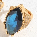Vista macro de un anillo dorado con gema azul marquesa y pavé de pedrería fina - Abierto Ajustable / Azul Real
