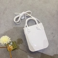 Borsa a mano bianca minimalista in PVC con manici annodati e tracolla su pietra - Bianco