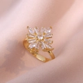Close-up of golden flower ring with spinning zircon stones on pink silk background - Petal Ring Style (J0219) / White