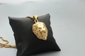 Macro shot of gold lion head pendant necklace displayed on a professional black jewelry pillow - Fashion Gold