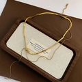 Minimalistische dubbellaagse gouden slangenschakelketting met centrale metalen knoop - Titanium Staal Dubbellaagse Slangenketting / Goud