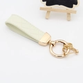 Beige gewatteerde leren sleutelhanger met gouden hoefijzersluiting en metalen ring - Gouden Hardware / Wit