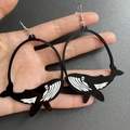 Detalle de un pendiente de ballena en acrílico blanco y negro sostenido a mano - Ballena