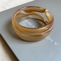 Detailed shot of amber marble acrylic cuff bracelet on a vintage book surface - Amber Texture (Light Coffee)