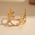 Dettaglio ravvicinato del bracciale a stella marina dorata con trama marina sulla sabbia - Stile Stella Marina con Texture Realistica / Oro