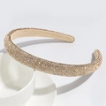 Close-up of luxury gold-tone headband with sparkling rhinestones on white ceramic - Gold