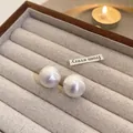 Close-up of elegant white acrylic pearl stud earrings placed in a beige velvet jewelry box - Medium (1.6cm) / White