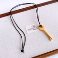Close-up of a vintage golden key pendant with black leather cord on a linen tray - Gold