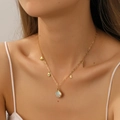Collar de acero de titanio dorado con colgante de concha usado por una modelo - Collar de Oro