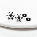 Détail macro de boucles d'oreilles flocon noires avec fermoirs sur surface blanche - Noir