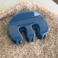 Vue détaillée d'une pince à cheveux en acrylique bleu brillant sur tissu beige doux - Bleu