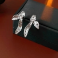 Macro detail of textured silver orchid petal earrings on dark jewelry box - Silver
