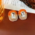 Vista macro detallada de pendientes vintage con esmalte naranja y cristales cuadrados - Aguja de plata / Naranja