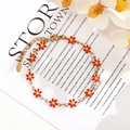 Detail view of gold stainless steel chain bracelet with red enamel daisy flower charms - Red