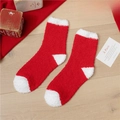 Flat lay of soft red and white fuzzy Christmas socks on a warm wooden background - Red with White Heel