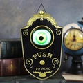 Black and gold Halloween eyeball doorbell with green glowing eye and PUSH TO RING text - Black