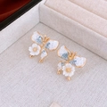 Detailopname van gouden vlinder oorbellen met blauwe kristallen in juwelendoos - Blauwe Vlinder Bloem (Zilveren Pin)