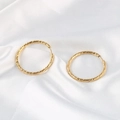 Pendientes redondos de oro texturizado vintage sobre fondo de seda blanca - Dorado