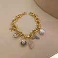 Detailed shot of gold-plated bracelet with starfish, seashell, and pearl charms - Ocean Series Pearl Bracelet