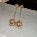 Dettaglio di lunghi orecchini pendenti in metallo dorato con doppie sfere su velluto - Pendaglio a Sfera Dorata / Oro