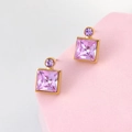 Elegant gold square pink crystal earrings on a matte pink pedestal with a grey background - Violet