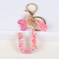 Pink resin letter U keychain with colorful floral sequins, pink butterfly and tassel - Letter U