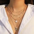 Multi-layer gold necklace featuring starfish, pearls and gold coin charms on a model - Gold Disc