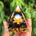Orgone pyramid featuring white crystal sphere, gold lotus and black stone base - Five Centimeters