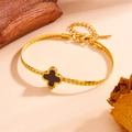 Detalle de collar de cadena barbada dorada con trébol negro sobre fondo de madera rústica - Trébol de Cuatro Hojas de Concha Negra (M710)