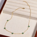 Detail view of a gold chain necklace with green gem flowers in a velvet jewelry box - Green Flower - Gold