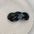 Detail showing a black glossy braided hair clip with gold France Handmade lettering - Black