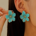 Nahaufnahme hellblauer Blumenohrstecker mit Goldrand an einem Frauenohr - KC Gold Blau (5519)