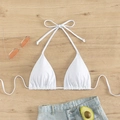 Flat lay of a white halter bikini top with tie straps and denim shorts on wood - White
