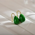 Makroansicht von smaragdgrünen Emaille-Ohrringen in Tropfenform mit goldenen Haken - Grün