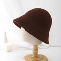 Close-up of a dark brown plush bucket hat on a mannequin head with minimalist background - Brown
