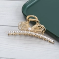 Dettaglio di una molletta per capelli in metallo dorato con perle e decorazione a fiocco - Stile Perla (D2235)
