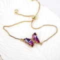 Detail of adjustable gold chain bracelet featuring a colorful crystal butterfly pendant - Fuschia