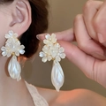 Detail of elegant pearl flower earrings with tassels and golden metal base on a woman - 54# Clustered Five-Petal Flower Drop Pearl Earrings (HE15735)