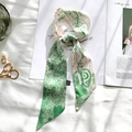 Detail view of satin silk scarf with green floral print and letter P on a magazine - Sketch Spring Letter P