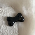 Barrette à cheveux noire en forme d'os avec texte doré sur une surface brillante - Os Noir