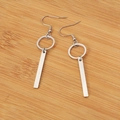Pendientes geométricos plateados con colgantes de aro y barra en fondo de madera - Color Acero