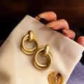 Close-up of gold matte irregular round earrings held by hand on a dark wooden surface - 13# Matte Gold Double Hoop Fashion Drop Earrings (13# Silver Earring Post-Pearl Gold-Round)