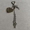 Silver heart-shaped keychain pendant with bow and long metal tassels on grey texture - Heart Mirror Style Set