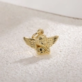 Macro shot of a gold-plated cupid angel wing pendant on a white stone background - Longing Angel