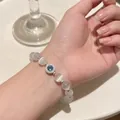 Cat eye bead bracelet with a blue zircon pendant in silver finish shown on hand - Silver/White Cat Eye