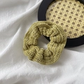 Detailed view of a green knitted scrunchie showing the soft texture on a wooden tray - Knitted Wool / Green