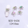 Close-up of 12x10mm alloy bow nail charms with colorful heart crystals on white nails - Silver Base Pink with Green Heart (9456)